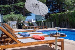 a pool with two chairs and a table with an umbrella at Torre Sant Genís in Llança