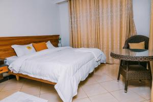 a bedroom with a large bed and a table at Neriah Suites in Kabale