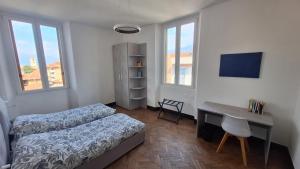 a bedroom with two beds and a desk and windows at Casa Tatta - Luino centro in Luino