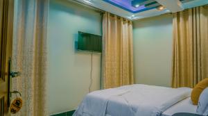 a bedroom with a bed and a flat screen tv at Neriah Suites in Kabale