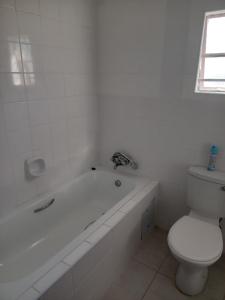 a white bathroom with a tub and a toilet at M's guest place Nata in Nata