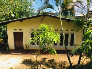 a small yellow house with a door and trees at Sansa HomeStay in Bandarawela