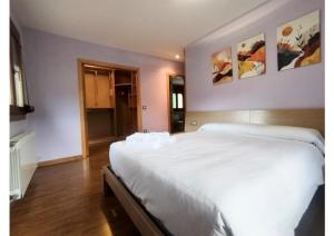 a bedroom with a large white bed with paintings on the wall at Check-in casas Mesón Casa Cereza in El Run