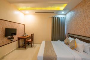 a bedroom with a bed and a desk and a television at Hotel Kiaara in Varanasi +30 photos