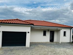 a white house with a garage with a red roof at L'évasion in Corent