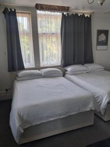 two beds in a bedroom with two windows at The Rising Sun in Rogerstone