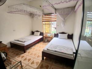 a room with two beds and a window at Nhà nghỉ Homestay Minh Hạnh in Nà Phia