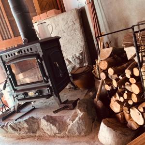 a stove in a room with a pile of logs at ゲストハウス やまんなか in Kamida