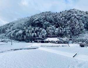 a snow covered mountain with a house in front of it at ゲストハウス やまんなか in Kamida +11 photos