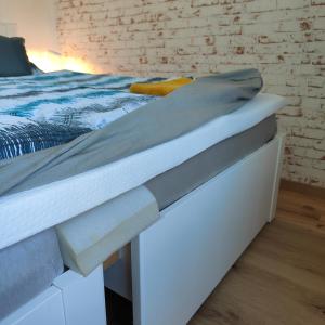 a white bed with grey sheets on top of it at Ferienwohnung Einsiedler - für 4 Personen mit Terrasse und Grill in Windisch Minihof