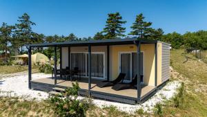 a tiny house with a deck in a field at Vela Stina Mobile home in Roč