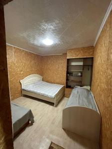 a bedroom with two beds in a room with a wall at Дом in Borovoye