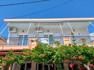 a white house with flowers on the balcony at ΠΗΛΙΟΣ ΦΩΤΙΟΣ in Loutsa