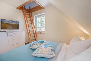 a bedroom with a ladder and a bed with pillows at Heimathafen An Seen & Meer in Korswandt