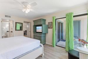 a bedroom with a bed and a television and a bathroom at Sea Woods 115 in New Smyrna Beach +47 photos