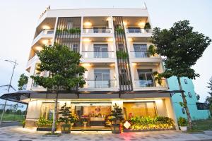 ein großes weißes Gebäude mit Bäumen davor in der Unterkunft May The Hotel in Cần Thơ