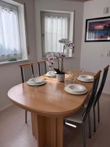 a wooden table with chairs and plates and flowers on it at Ferienwohnung Martin in Neuhausen ob Eck +1 photo