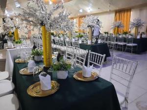 a table with a green table cloth and white chairs at GLAMOSSAY HOTEL LIMITED SUNYANi in Abesem