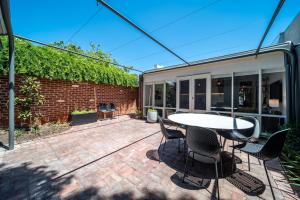 a patio with a table and chairs and a brick wall at Wisteria Cottage circa 1880 in North Adelaide