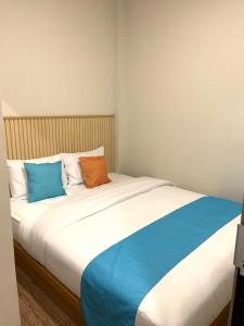 a large bed with blue and orange pillows on it at Sera INN Cikarang in Jatirarangan