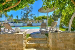 a patio with chairs and an umbrella next to a pool at Nautilus Villa - Private Pool in Elaía +21 photos