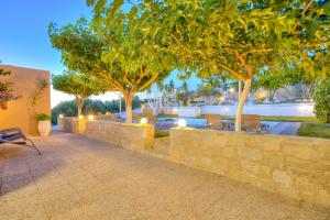 a patio with trees and a stone wall at Nautilus Villa - Private Pool in Elaía