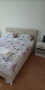 a bed with a floral comforter and pillows on it at Apartman Miljan in Trebinje
