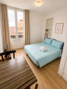 a bedroom with a bed and a table and a window at Résidence Appartement Adonis in Nice