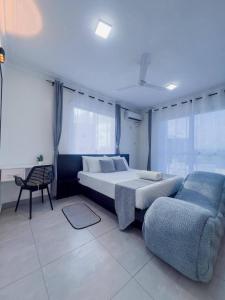 a bedroom with a bed and a couch and windows at The palace001 in Mombasa