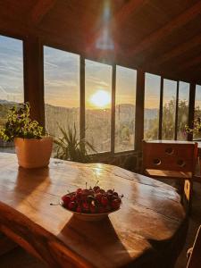 a bowl of cherries on a wooden table with a view at VEIS Country House in Kamenicë