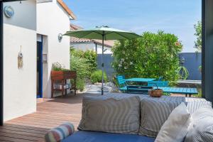 a patio with a couch and an umbrella at Chambres D'hôtes Authentique Pornic in Pornic +19 photos