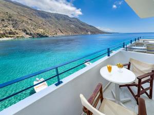 a table and chairs on a balcony overlooking the water at Sifis in Loutro