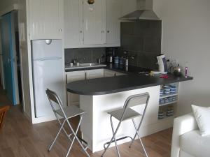 a kitchen with a black counter and two chairs at Appart avec terrasse proche mer in Macinaggio
