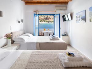 two beds in a room with a view of the ocean at Sifis in Loutro