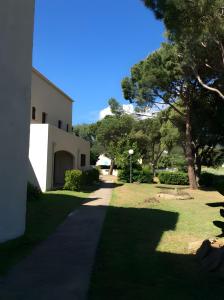 a walkway in front of a building with trees at Appart avec terrasse proche mer in Macinaggio