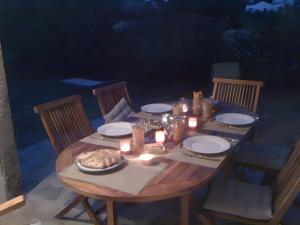 a wooden table with candles and plates and a table with chairs at Appart avec terrasse proche mer in Macinaggio