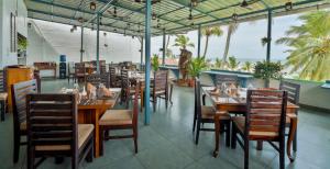 a restaurant with wooden tables and chairs and the ocean at Getaway Beach Resort Kovalam in Kovalam