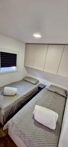 two beds in a small room with a window at Mobile Homes Gasperino in Pirovac