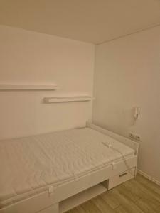 a small white bedroom with a bed in it at Helles Apartment mit Self Check-in in Nuremberg