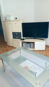 a glass table with a tv on top of it at Apartment SAYA in Banja Luka