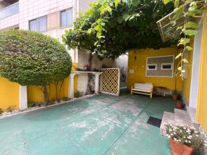 a patio with a bench and a yellow building at Hostel das Flores in Senhora da Hora