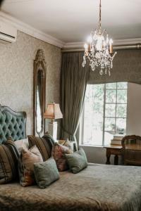 a bedroom with a bed with a chandelier at Godiva Spa & Guesthouse in Groblersdal