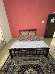 a bed in a room with a red wall at RoyalNest Gardenia in Belgaum