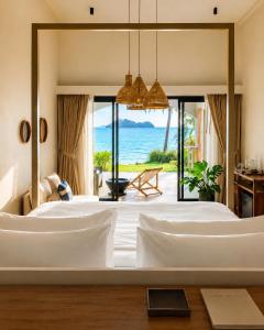 a bedroom with a bed with a view of the ocean at Baan Jai Dee Beach Front Hotel in Wok Tum