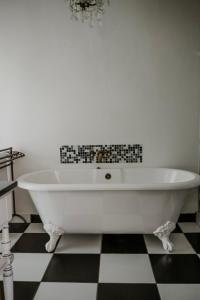 a white bath tub in a bathroom with a checkered floor at Godiva Spa & Guesthouse in Groblersdal +106 photos