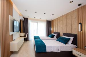 two beds in a hotel room with a television at Premium Apartments Zevs in Budva