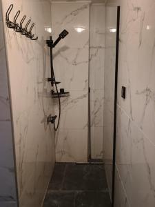 a bathroom with a shower with white marble walls at u Oli Dawid Spaczyński in Mrzeżyno