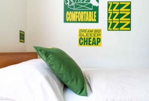 a bedroom with a bed with a green pillow at SLEEEP Hotel Sattledt in Sattledt