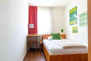 a bedroom with a bed and a desk and a window at SLEEEP Hotel Sattledt in Sattledt