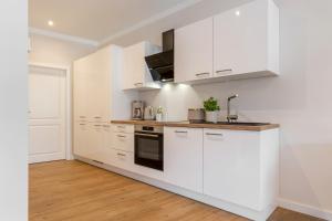 a white kitchen with white cabinets and appliances at Mellenthin-Lodges "Seeigel" in Fehmarn
